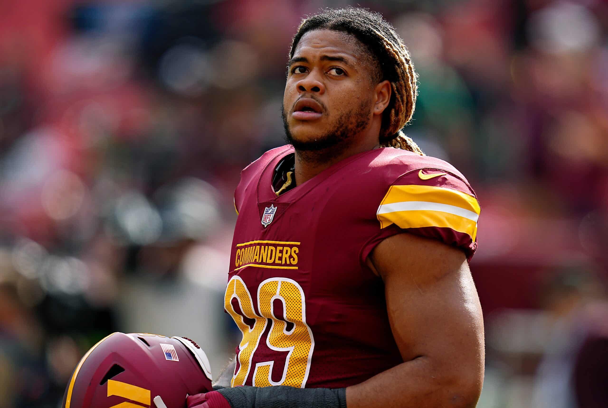 CHASE YOUNG SOSTIENE SU CASCO EN LA BANCA DURANTE UN PARTIDO CON LOS COMMANDERS