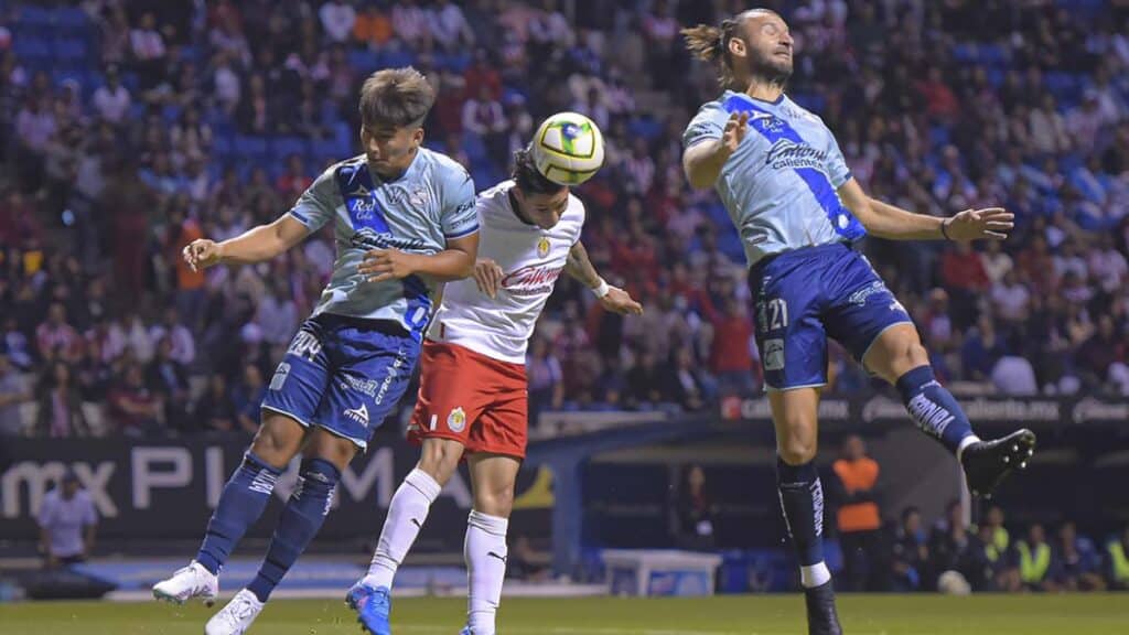Jugadores de ambos equipos peleando un balón aéreo