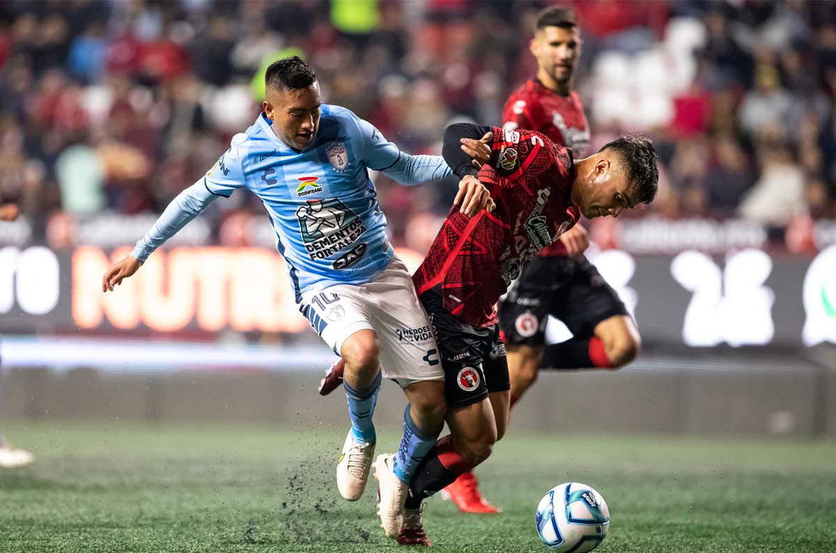 Erick Sanchez compitiendo por el balón ante un defensa de Xolos