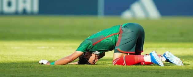 Jugador de rodillas con la frente en el césped