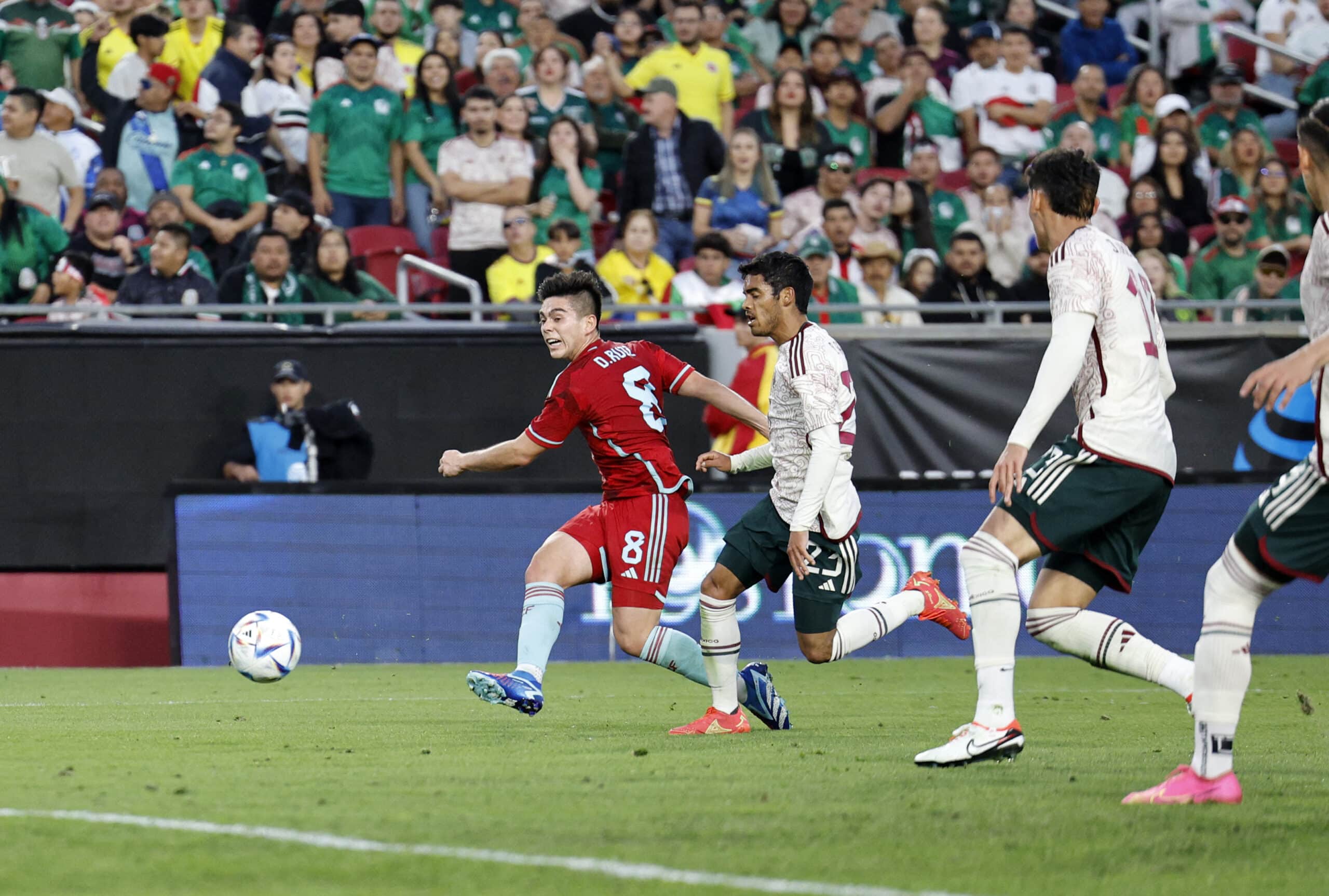 Jugador de Colombia remata a gol ante la marca de un defensa azteca.