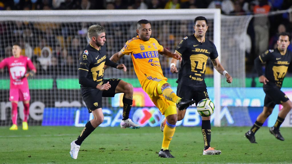 Jugador de Tigres trata de controlar el balón ante la marca de dos jugadores de Pumas.