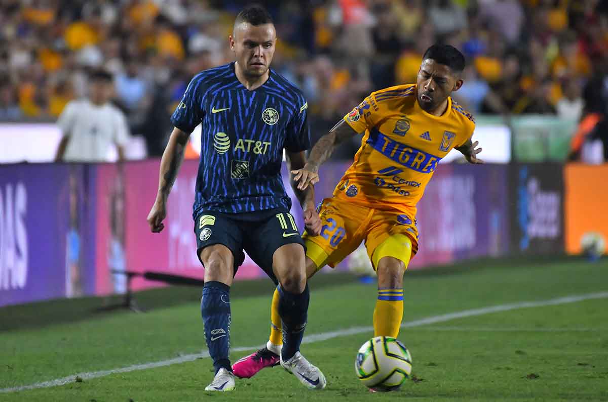 Jonathan Rodríguez defiende el balón ante la marca de un jugador de Tigres.