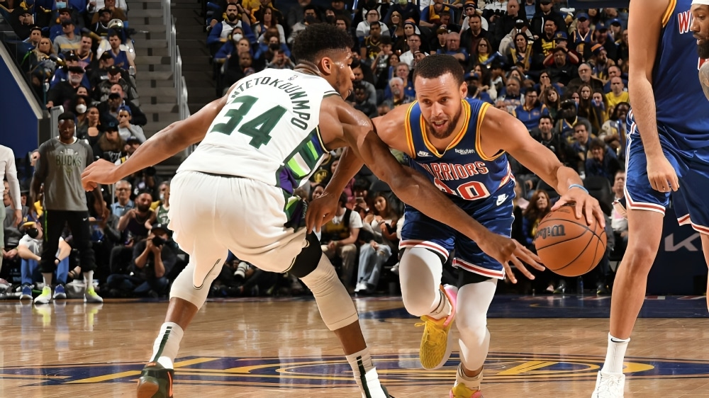 GIANNIS ANTETOKOUNMPO DE LOS BUCKS A LA IZQUIERDA, DEFENDIENDO A STPEHEN CURRY A LA DERECHA DE LOS WARRIORS