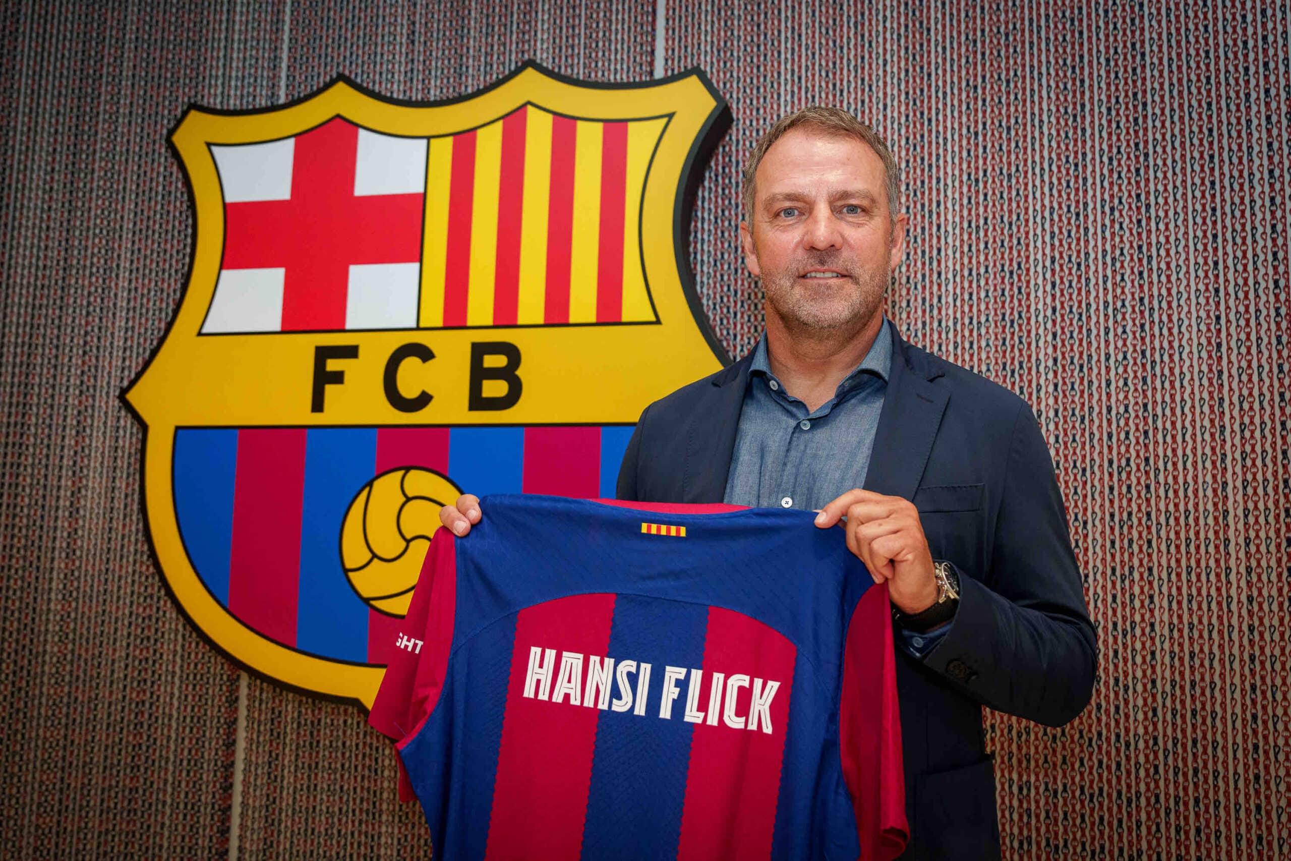HANSI FLICK POSA PARA LA FOTO CON LA PLAYERA DEL BARCELONA Y EL ESCUDO DEL CLUB