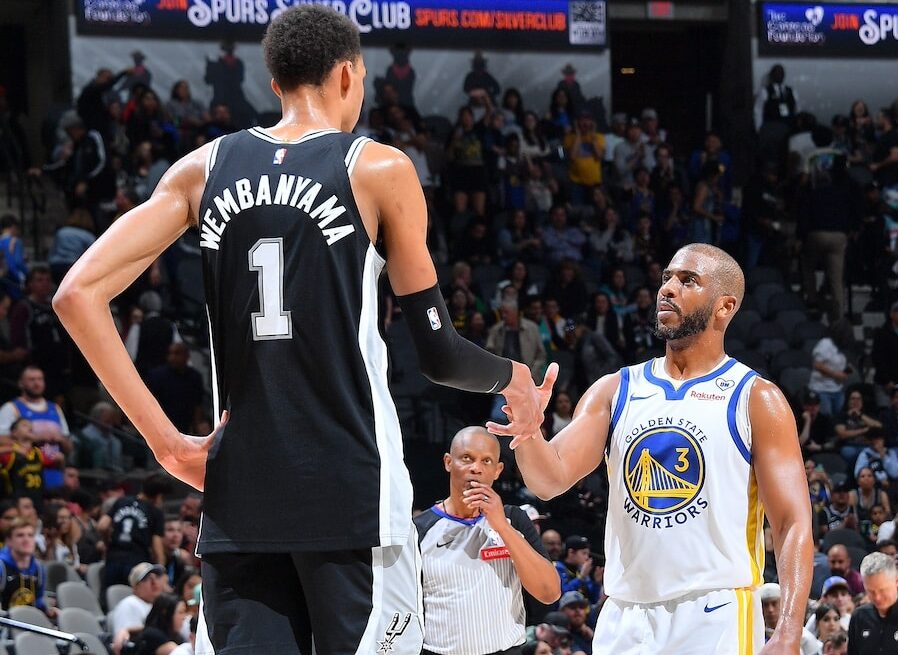 VÍCTOR WEMBANYAMA SALUDA A CHRIS PAUL DURANTE UN JUEGO ENTRE SPURS Y WARRIORS EN LA NBA